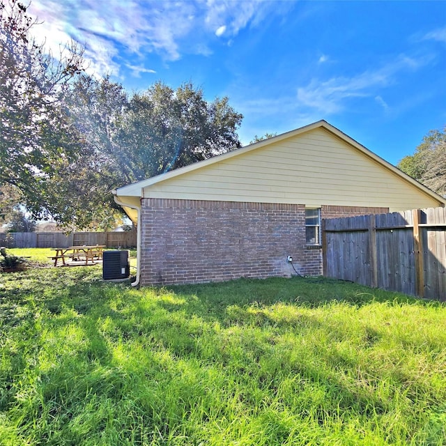 view of side of home with a yard and central AC