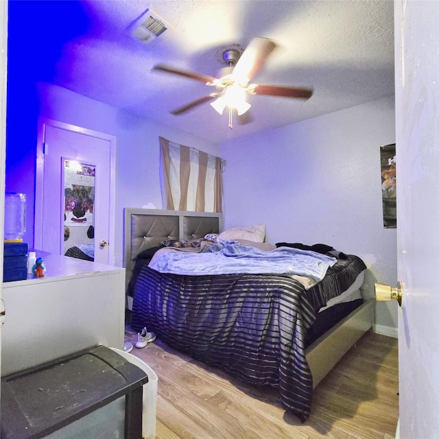 bedroom with hardwood / wood-style floors, a textured ceiling, and ceiling fan