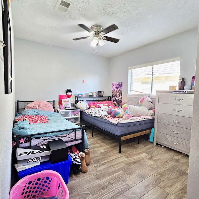 bedroom featuring light wood-type flooring, a textured ceiling, and ceiling fan