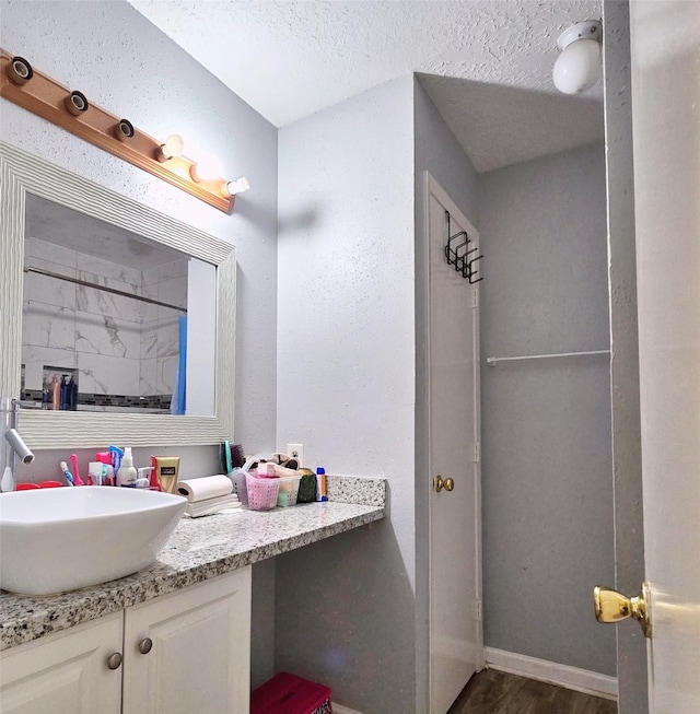 bathroom with wood-type flooring, vanity, a textured ceiling, and a shower