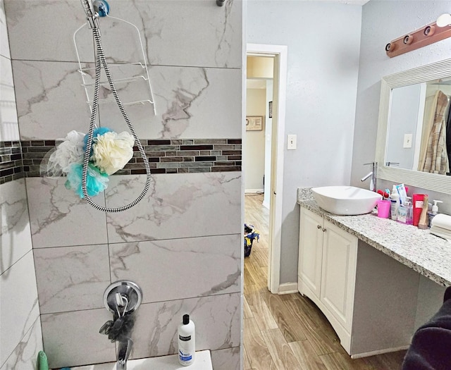 bathroom featuring wood-type flooring, vanity, and tiled shower