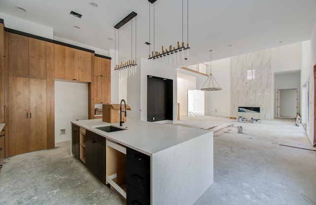 kitchen with a center island with sink, pendant lighting, sink, and a high end fireplace