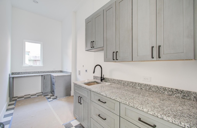 kitchen featuring gray cabinetry, light stone counters, and sink