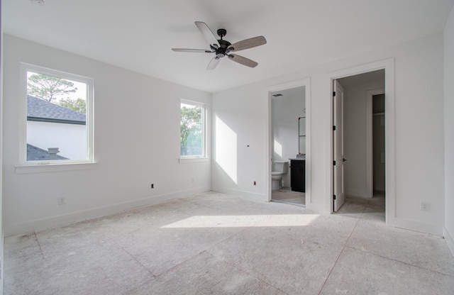 unfurnished bedroom with a walk in closet, ensuite bath, and ceiling fan