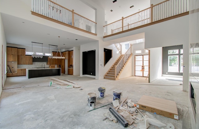 unfurnished living room featuring a towering ceiling and sink