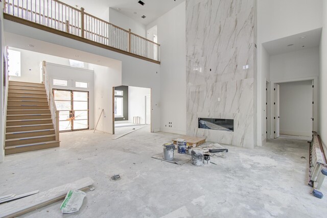 unfurnished living room with a high ceiling, concrete floors, and a premium fireplace