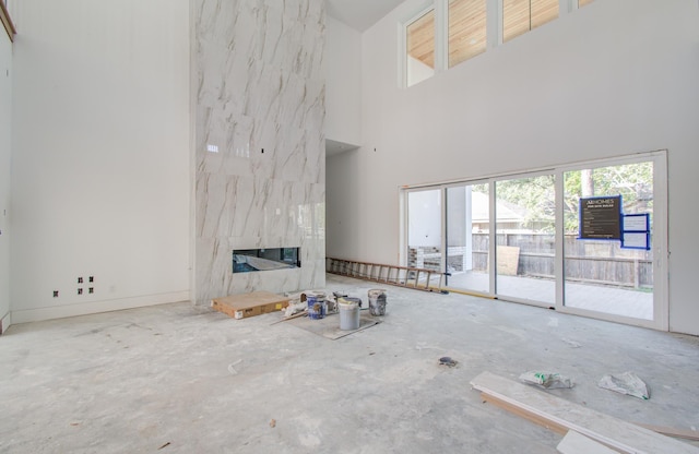 unfurnished living room featuring a premium fireplace, a high ceiling, and concrete floors