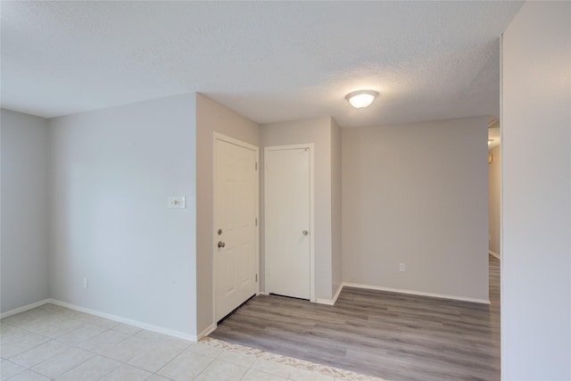 unfurnished room with a textured ceiling and light hardwood / wood-style flooring