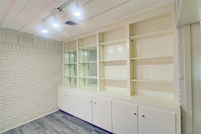 interior space with beam ceiling, white cabinetry, wood-type flooring, and track lighting