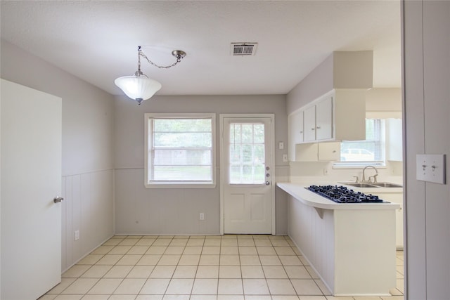 kitchen with white cabinets, a healthy amount of sunlight, kitchen peninsula, and hanging light fixtures