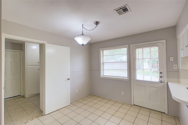 unfurnished dining area with light tile patterned floors and a textured ceiling