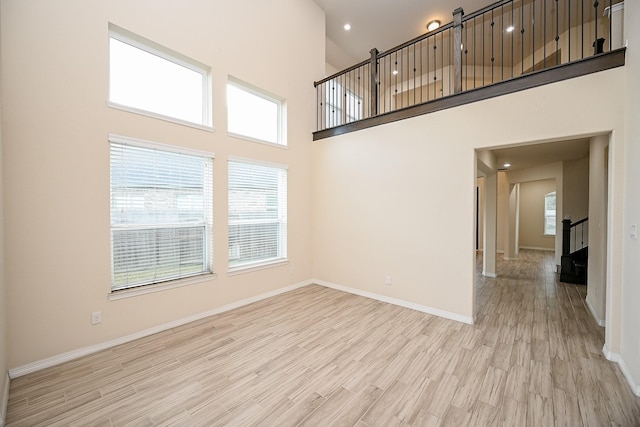 unfurnished living room with light hardwood / wood-style floors and a high ceiling