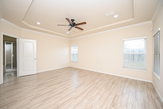 empty room featuring light wood-type flooring, a raised ceiling, ceiling fan, and crown molding