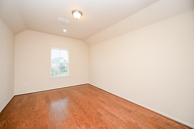 empty room with light hardwood / wood-style floors and vaulted ceiling