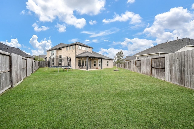 back of house with a lawn, a trampoline, and a patio