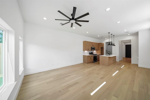 unfurnished living room with ceiling fan, light hardwood / wood-style floors, and sink