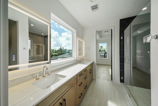 bathroom featuring vanity, a shower with door, and a wealth of natural light