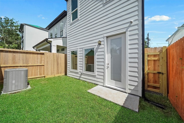 rear view of property with central AC unit and a lawn