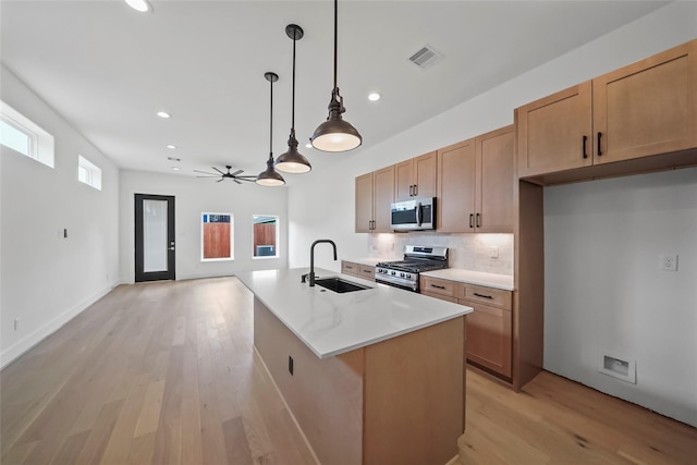 kitchen featuring sink, a center island with sink, appliances with stainless steel finishes, pendant lighting, and ceiling fan