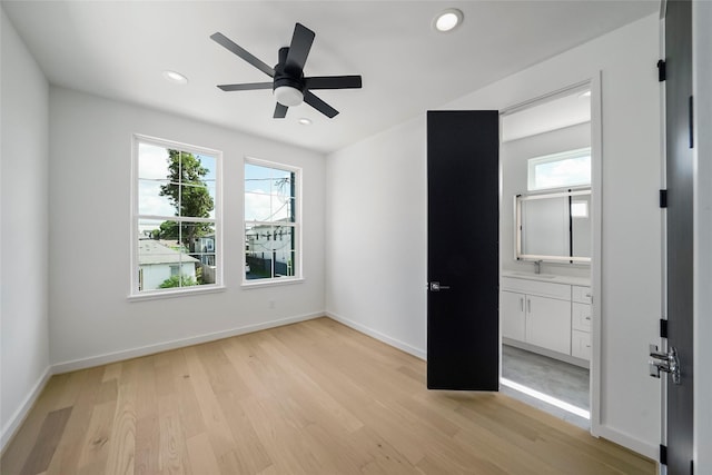 unfurnished bedroom with ceiling fan, ensuite bath, sink, and light hardwood / wood-style flooring