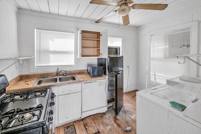 kitchen with sink, black appliances, washer / dryer, light hardwood / wood-style floors, and white cabinetry