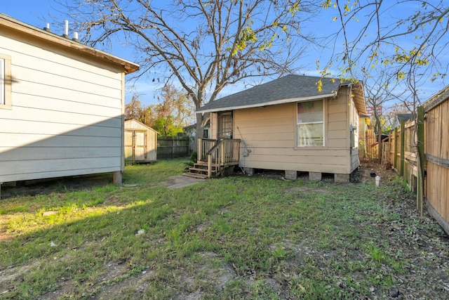 rear view of property featuring a yard and a storage unit