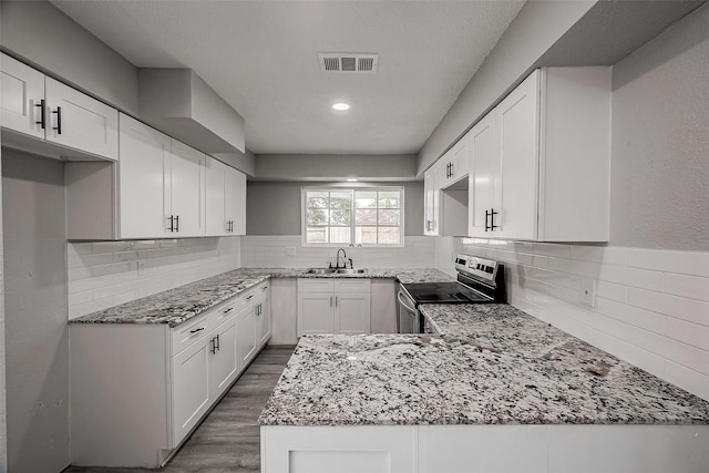 kitchen with stainless steel range with electric cooktop, white cabinets, light stone countertops, dark hardwood / wood-style flooring, and kitchen peninsula