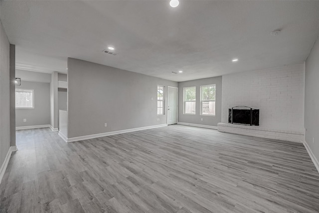 unfurnished living room featuring light hardwood / wood-style floors and a brick fireplace