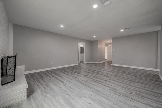 unfurnished living room featuring a textured ceiling and light hardwood / wood-style flooring