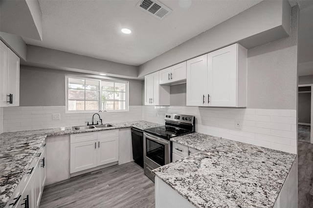 kitchen featuring light stone countertops, sink, electric stove, light hardwood / wood-style flooring, and white cabinets