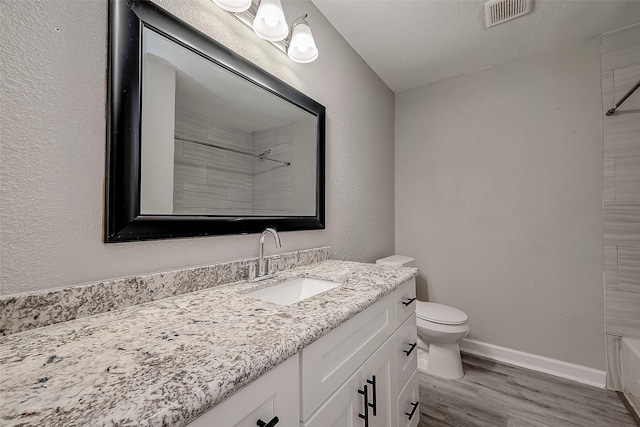 bathroom with hardwood / wood-style floors, vanity, toilet, and a textured ceiling