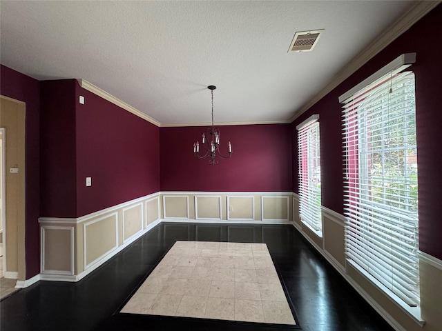 unfurnished dining area featuring a chandelier, a textured ceiling, dark wood-type flooring, and crown molding