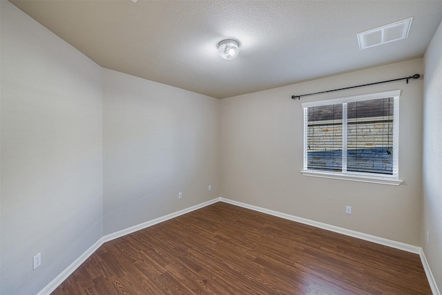 unfurnished room with a textured ceiling and dark hardwood / wood-style floors