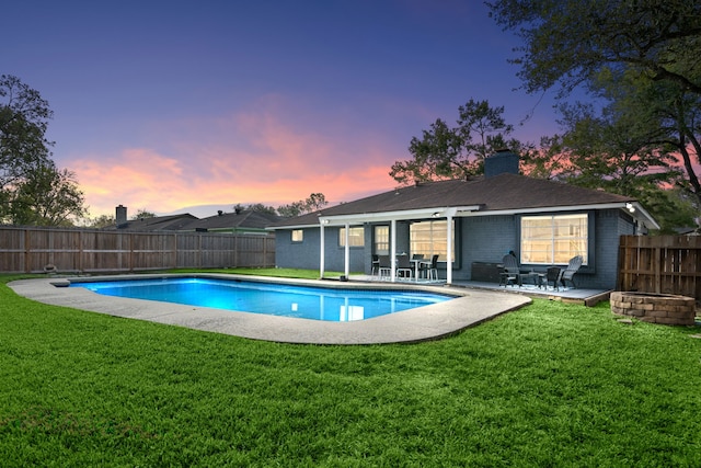 pool at dusk with a patio area and a yard