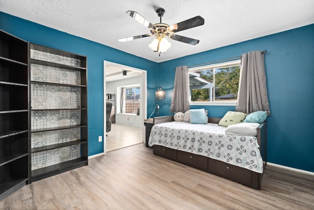 bedroom featuring ceiling fan, light hardwood / wood-style floors, and a textured ceiling