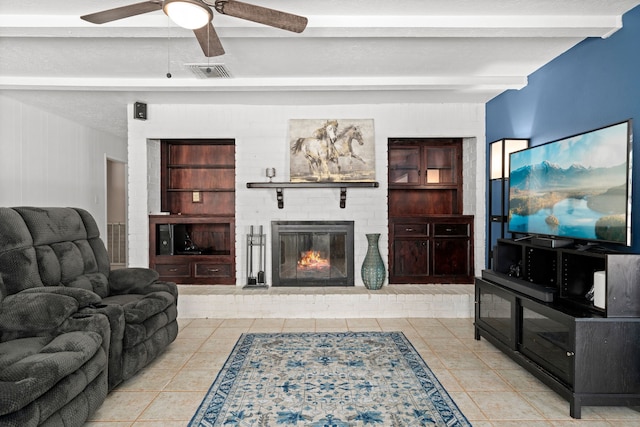 living room featuring beam ceiling, built in shelves, ceiling fan, a fireplace, and light tile patterned floors