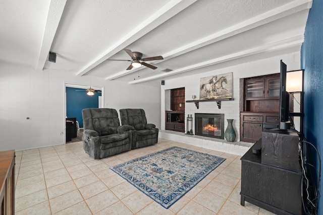 tiled living room with beam ceiling, ceiling fan, a fireplace, and a textured ceiling