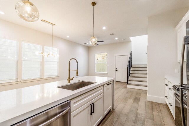 kitchen with dishwasher, sink, hanging light fixtures, light hardwood / wood-style flooring, and white cabinets