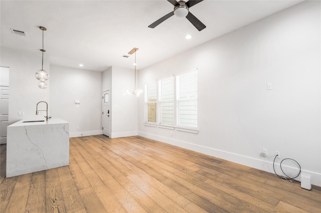 interior space with ceiling fan, sink, and light hardwood / wood-style flooring