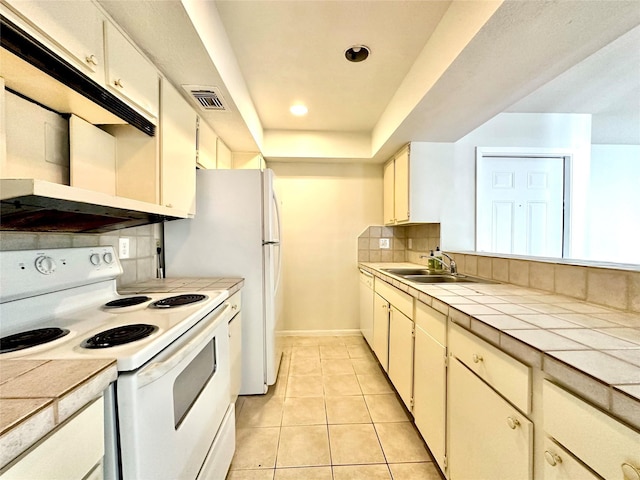 kitchen featuring white range with electric stovetop, sink, tasteful backsplash, tile counters, and light tile patterned flooring