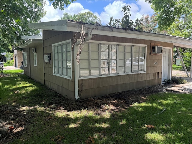 view of home's exterior featuring a lawn and an AC wall unit