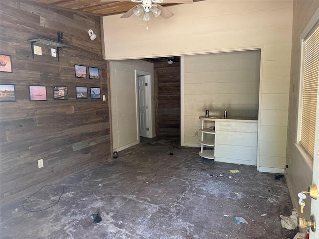 unfurnished living room with wooden walls and ceiling fan