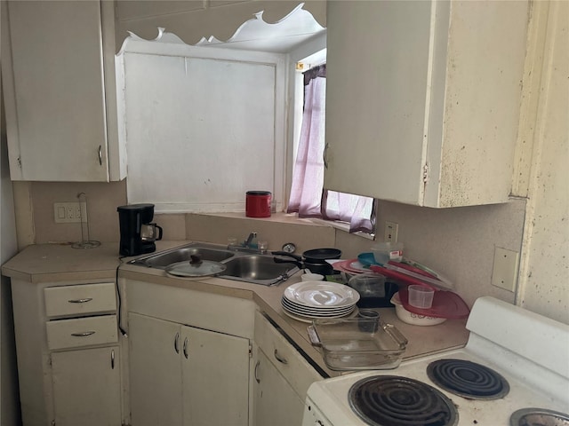 kitchen featuring white cabinets, white range oven, and sink