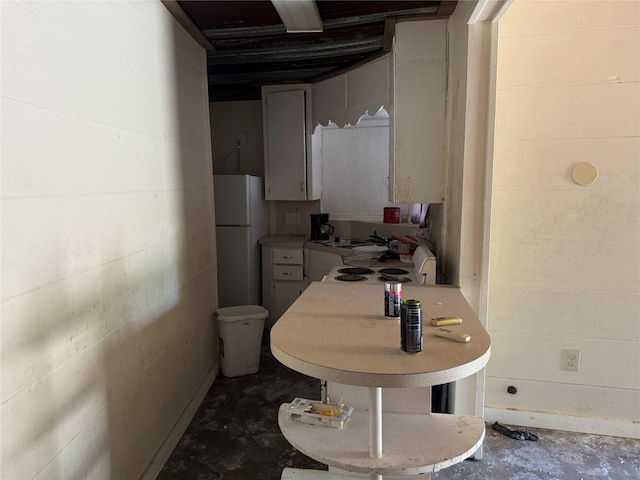 kitchen with white refrigerator and concrete floors