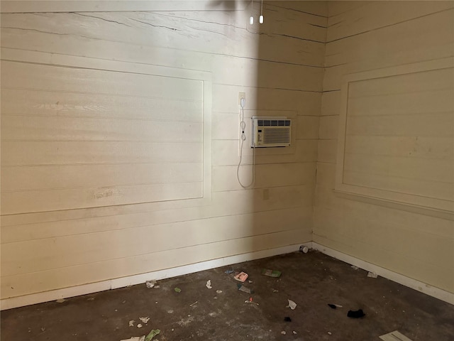 basement featuring a wall mounted air conditioner and wooden walls