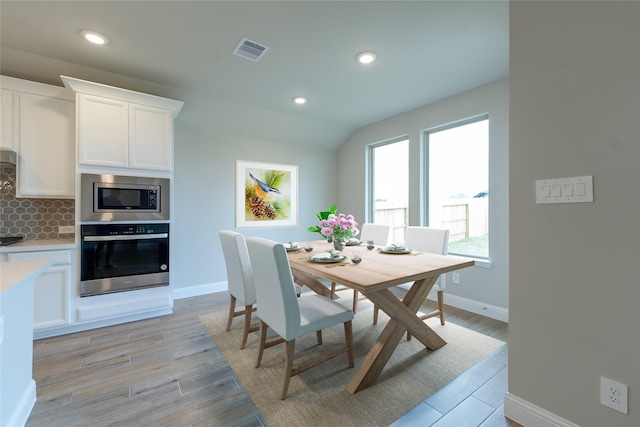 dining room featuring vaulted ceiling and light hardwood / wood-style flooring