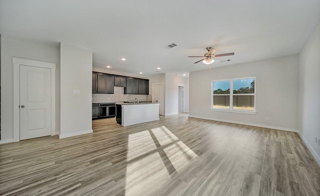 unfurnished living room featuring light wood-type flooring, ceiling fan, and sink