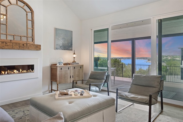 living room with hardwood / wood-style floors, a water view, and vaulted ceiling