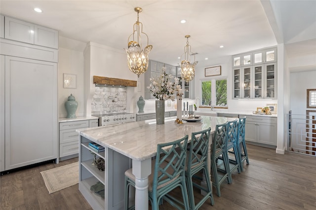 kitchen featuring a kitchen bar, light stone countertops, electric stove, dark hardwood / wood-style floors, and a kitchen island