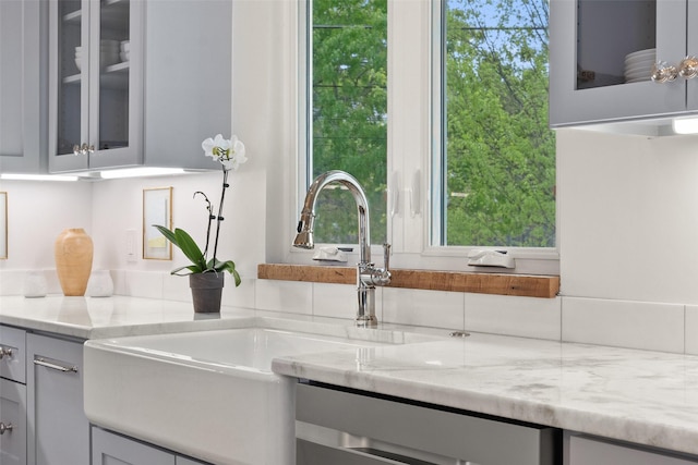 room details with light stone countertops, sink, and stainless steel dishwasher